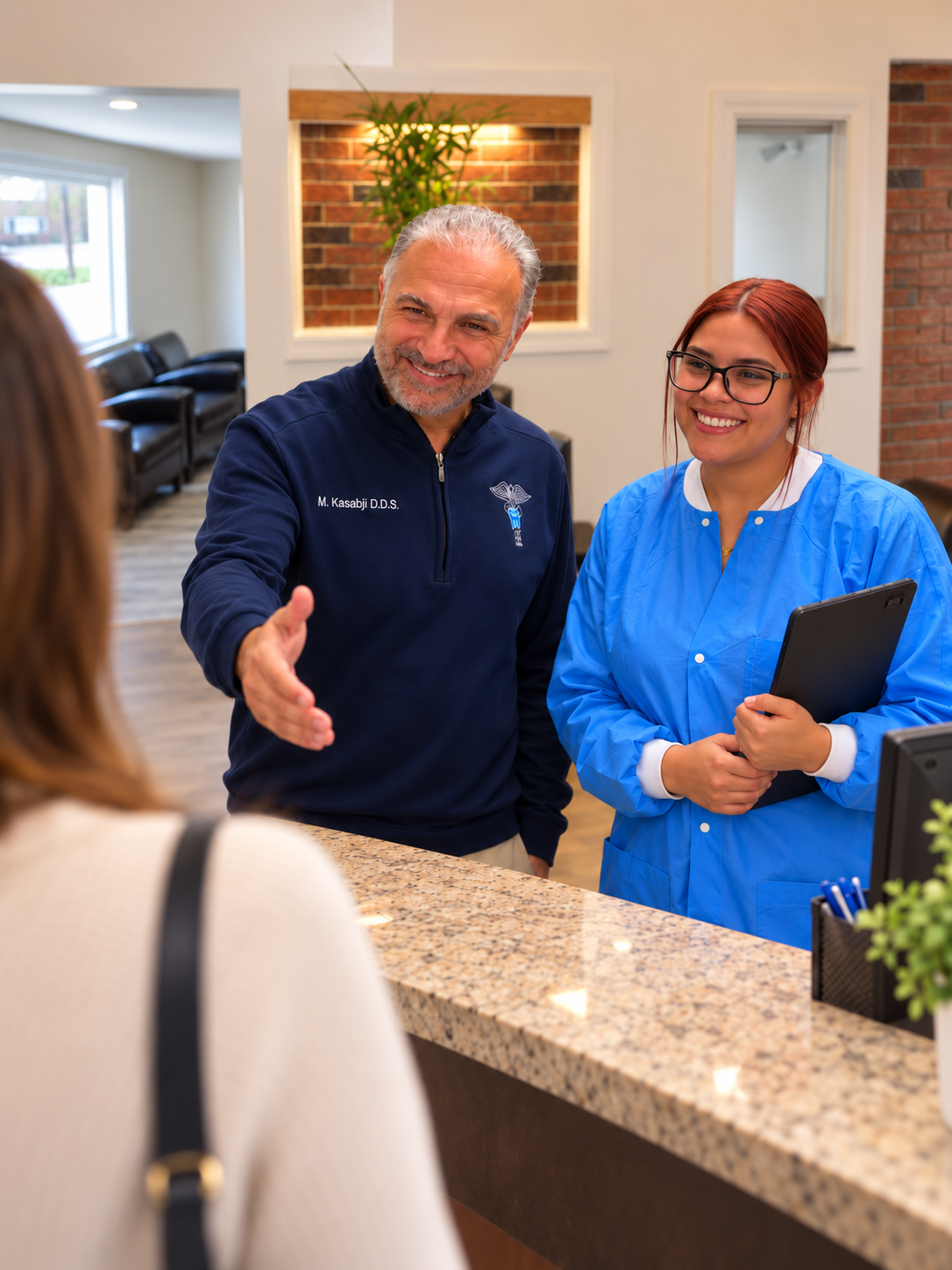 Dr. Maher Kasabji and a team member welcoming a patient at the reception desk of Family Dental Center of Connecticut in Wethersfield, CT